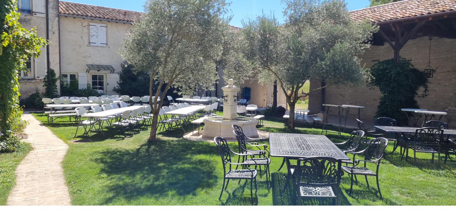 The courtyard set for a banquet — long tables, olive trees and the central fountain.