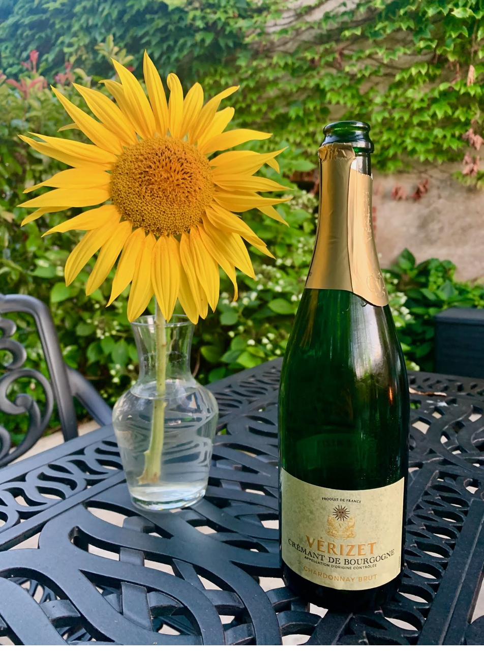A bottle of Crémant de Bourgogne and a sunflower on the garden table.