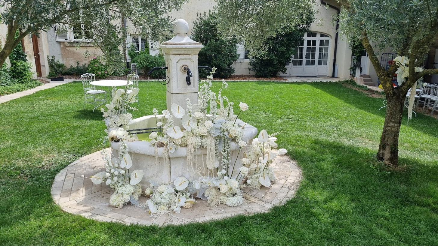 The garden fountain dressed with white floral arrangements for a wedding.